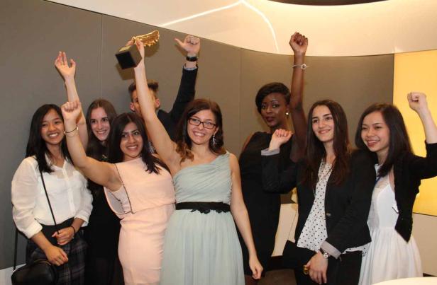 Eine Gruppe junger Leute jubelt mit erhobenen Armen und einer goldenen Trophäe.