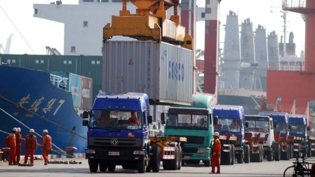 Ein Kran hebt einen Container auf einen Lastwagen im Hafen.
