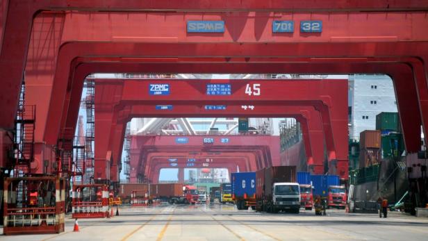 Ein Containerterminal mit roten Kränen und Lastwagen.