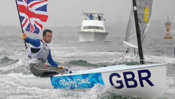 Ein Segler mit der britischen Flagge auf einem Segelboot mit der Aufschrift „Beijing 2008“.