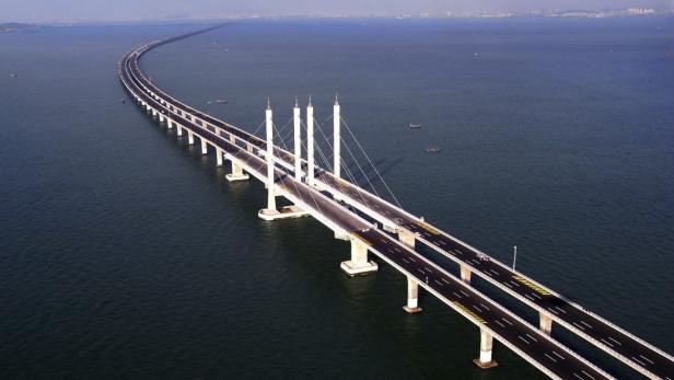 Eine lange Brücke mit mehreren Fahrspuren überquert das Meer.
