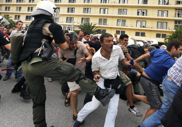 Ein Polizist in Kampfmontur tritt einen Demonstranten während einer Auseinandersetzung.