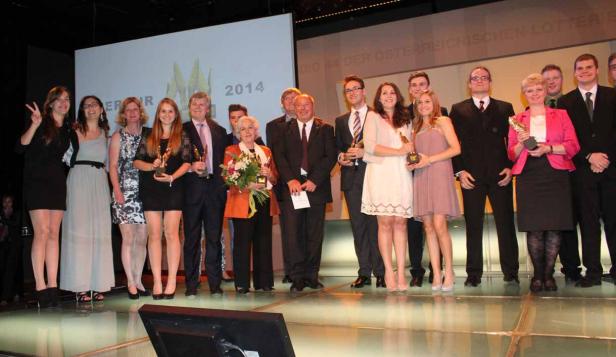 Eine Gruppe von Preisträgern steht auf einer Bühne und hält Trophäen in den Händen.