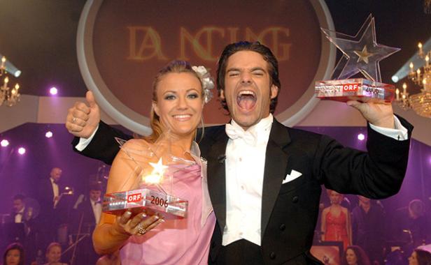 Ein Mann im Smoking und eine Frau mit einem Kleid halten Trophäen bei „Dancing Stars“.