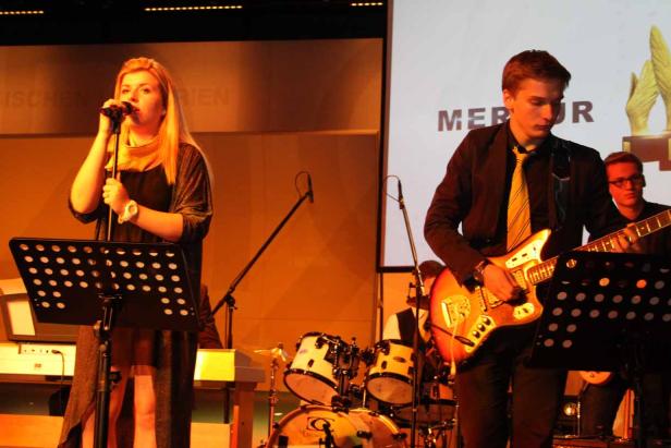 Eine Sängerin und ein Gitarrist treten mit ihrer Band auf einer Bühne auf.