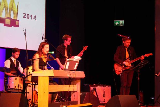 Eine Band spielt auf einer Bühne mit Keyboard, Schlagzeug und Gitarren.