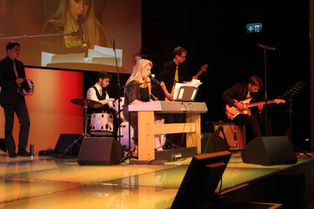 Eine Band spielt auf einer Bühne mit Schlagzeug, Keyboard und Gitarren.