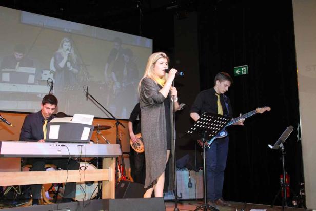 Eine Sängerin tritt mit ihrer Band auf einer Bühne auf.