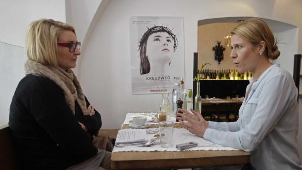 Zwei Frauen sitzen an einem Tisch in einem Café und unterhalten sich.