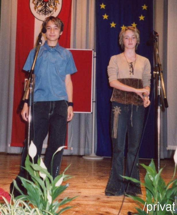 Zwei Jugendliche stehen auf einer Bühne vor der österreichischen und der europäischen Flagge.