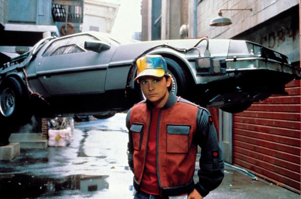 Michael J. Fox steht vor dem fliegenden DeLorean aus „Zurück in die Zukunft II“.