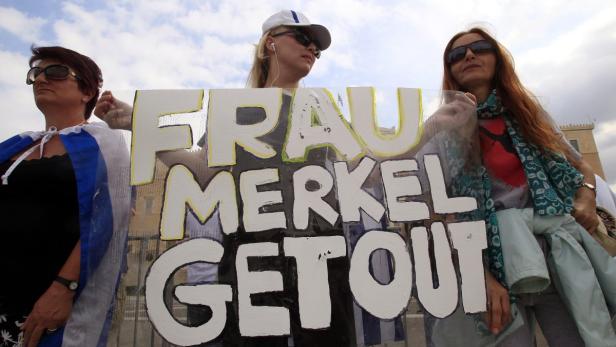 Drei Frauen halten ein Schild mit der Aufschrift „Frau Merkel Get Out“.