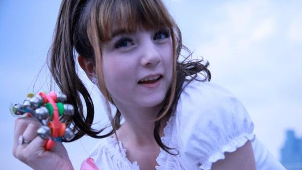 Eine junge Frau hält ein Schelleninstrument in der Hand.