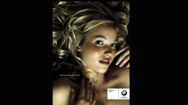 Eine blonde Frau liegt auf dem Rücken und blickt in die Kamera.