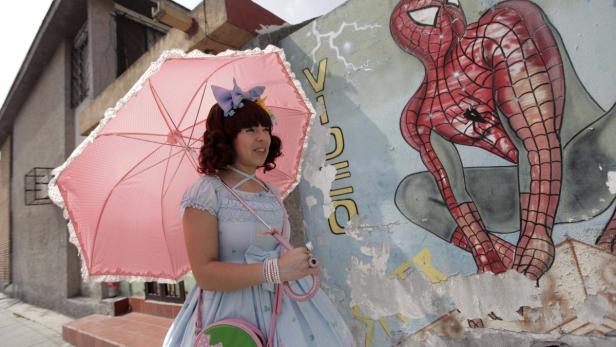 Eine junge Frau im Lolita-Stil posiert vor einem Graffiti von Spider-Man.