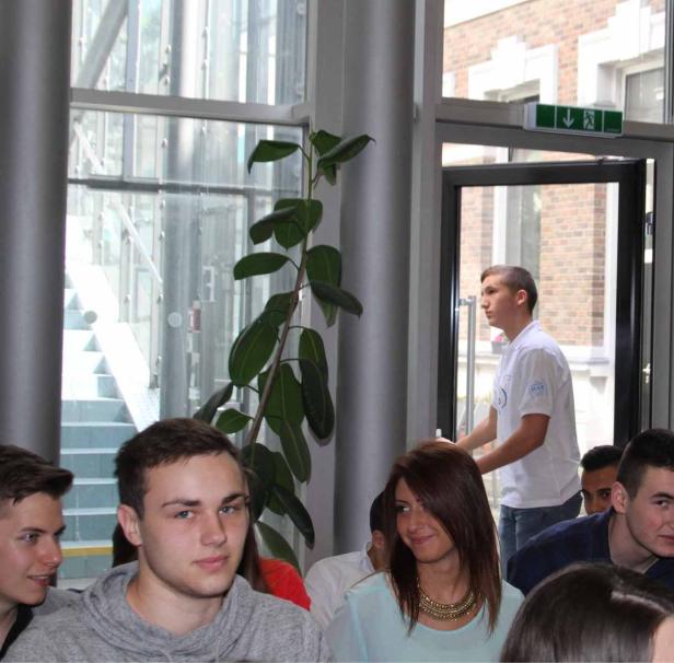 Eine Gruppe junger Leute sitzt in einem hellen Raum mit großen Fenstern.