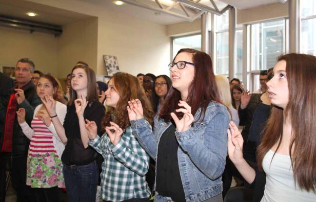 Eine Gruppe junger Leute blickt aufmerksam nach oben und formt mit den Händen Kreise.