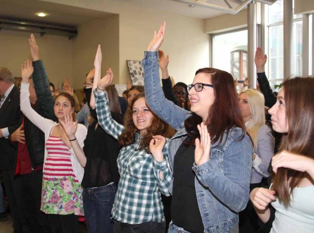 Eine Gruppe junger Leute hebt die Hände in die Luft.