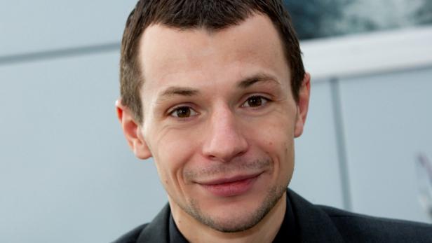 Ein lächelnder Mann mit braunen Augen und dunklen Haaren blickt in die Kamera.
