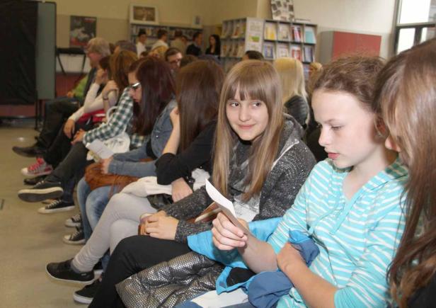 Eine Gruppe von Jugendlichen sitzt in einem Raum und liest etwas.