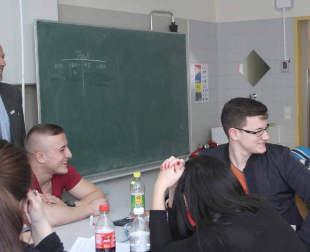 Eine Gruppe von Schülern sitzt in einem Klassenzimmer und unterhält sich.