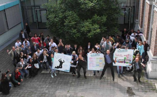 Eine Gruppe von Menschen hält Schilder mit der Aufschrift „Luftsprung“ und „Deine Idee“.