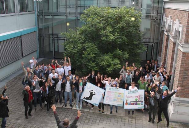 Eine Gruppe von Menschen springt mit Plakaten im Freien in die Luft.