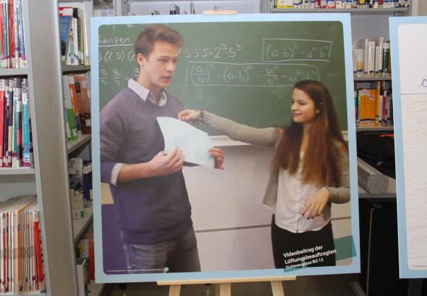 Ein junger Mann und eine junge Frau stehen vor einer Tafel mit mathematischen Formeln.