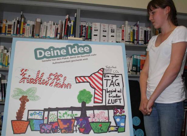 Ein junges Mädchen steht vor einem Plakat zum Thema Raumluftverbesserung.