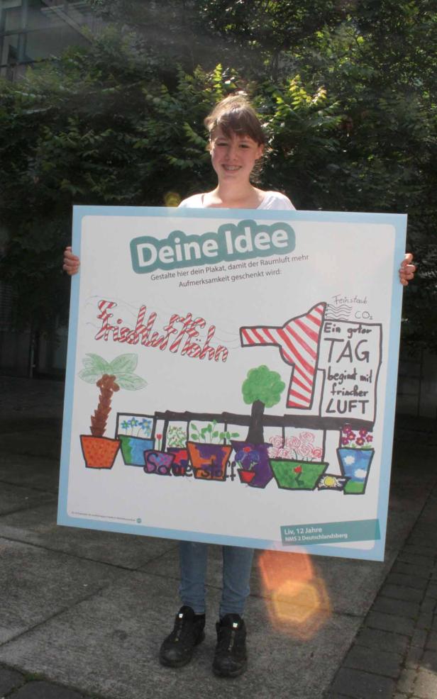 Ein junges Mädchen hält ein Plakat mit einer Zeichnung zum Thema „Frischluft“.