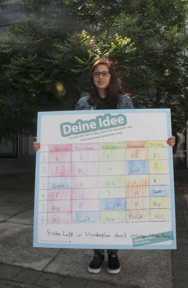 Eine junge Frau hält ein Plakat mit einem Stundenplan in der Hand.