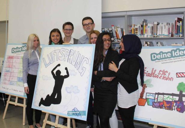 Eine Gruppe von Schülerinnen und Schülern präsentiert ihre Plakate zum Thema „Luftsprung“.