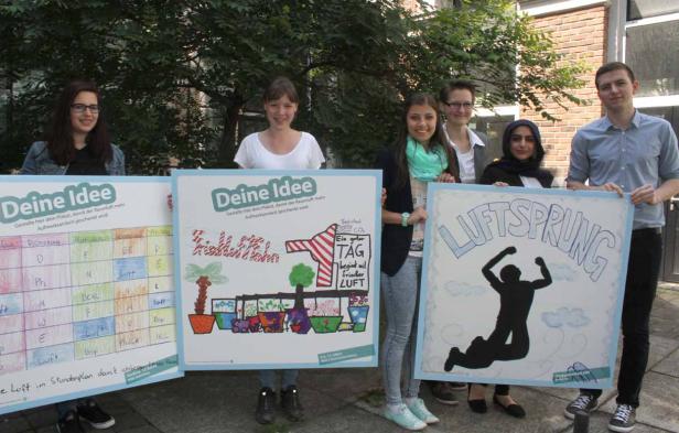 Eine Gruppe junger Leute präsentiert Plakate zum Thema Luftqualität und Umweltschutz.