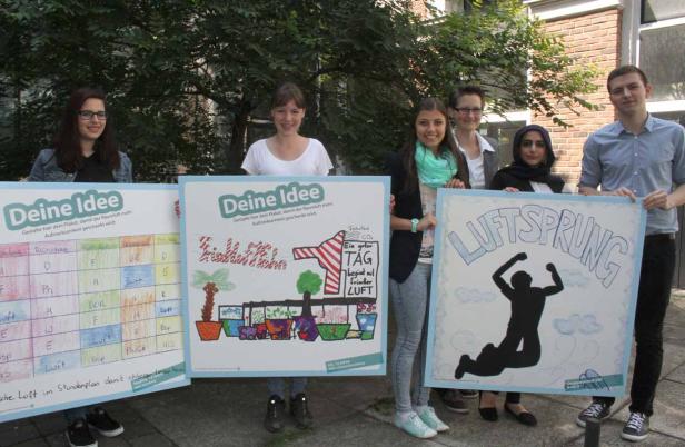 Eine Gruppe junger Leute präsentiert Plakate mit dem Thema Raumluft in Innenräumen.