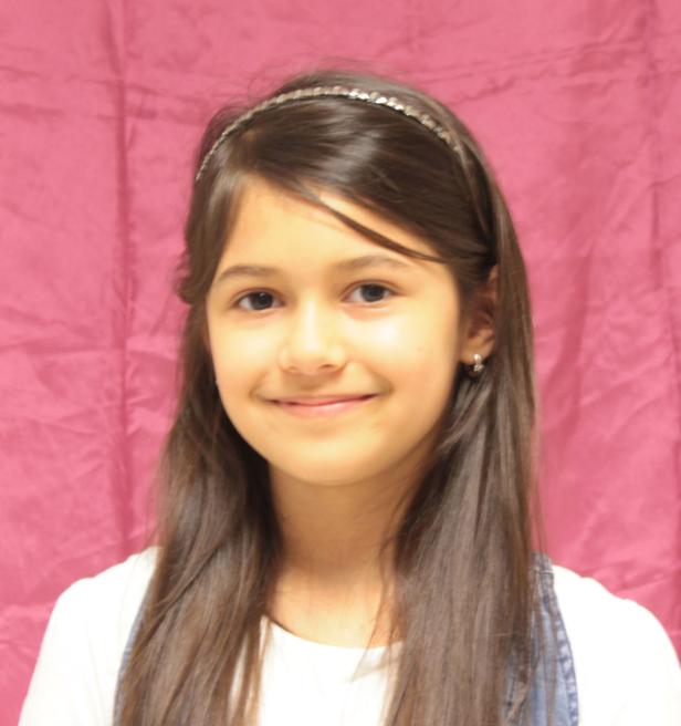 Ein junges Mädchen mit braunen Haaren und einem Haarband lächelt.