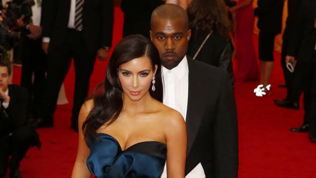 Kim Kardashian und Kanye West posieren auf einem roten Teppich.