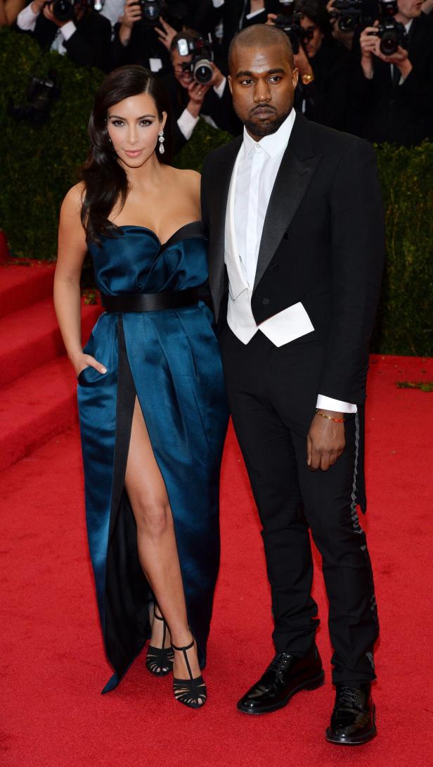 Kim Kardashian und Kanye West posieren auf einem roten Teppich.