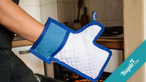 Eine Person mit einem Ofenhandschuh vor einem geöffneten Backofen.