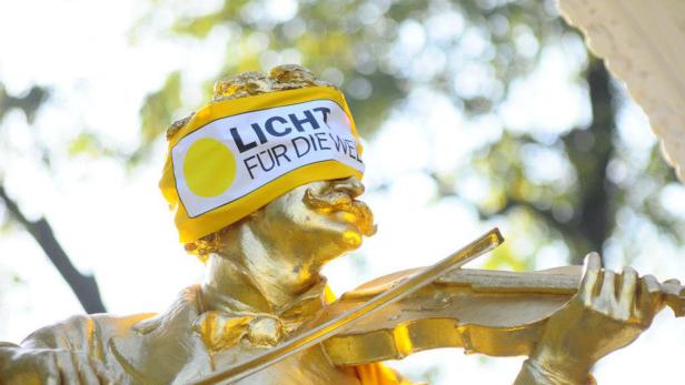 Eine goldene Statue eines Geigers mit einer Binde mit der Aufschrift „Licht für die Welt“.