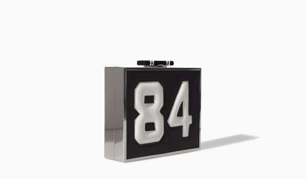 Eine schwarze Handtasche in Form eines Quadrats mit der Nummer 84 darauf.