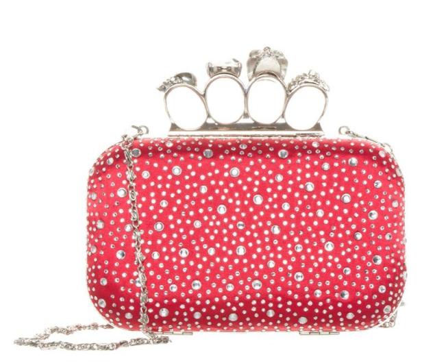 Eine rote Clutch mit silberner Kette und einem Griff mit vier Ringen, die mit Strasssteinen besetzt sind.