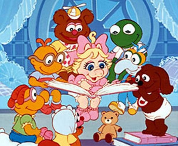 Die Muppet Babies sitzen im Kreis und hören Miss Piggy zu, die aus einem Buch vorliest.