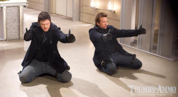 Zwei Männer knien mit erhobenen Daumen auf dem Boden.