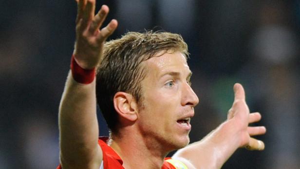 Ein Fußballspieler gestikuliert mit erhobenen Händen.