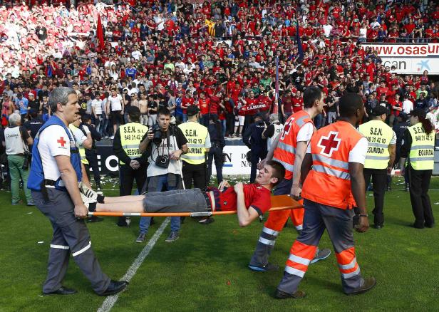 Sanitäter tragen einen verletzten Fußballspieler auf einer Trage vom Spielfeld.