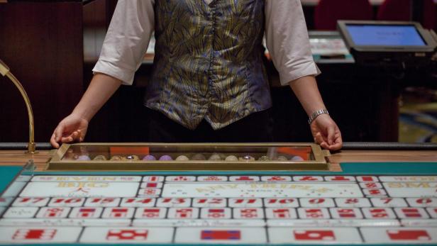 Ein Croupier steht an einem Tisch für Glücksspiele im Kasino.