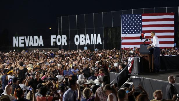 Barack Obama spricht vor einer großen Menschenmenge mit einer US-Flagge und dem Schriftzug „Nevada for Obama“ im Hintergrund.