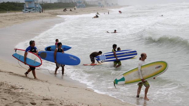 Mehrere Surfer gehen mit ihren Surfbrettern ins Wasser.