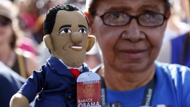 Eine ältere Frau hält eine Barack Obama-Puppe der Marke „Little Thinkers“.