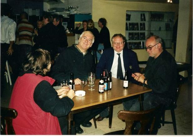 Eine Gruppe von Menschen sitzt an einem Tisch mit Bierflaschen in einem Lokal.